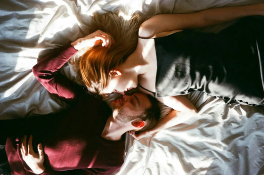 Couple resting peacefully on crisp white bamboo bedding, bathed in warm morning sunlight. The soft, breathable bamboo sheets showcase their natural drape and comfort, highlighting how sustainable bedding enhances sleep quality and intimacy.