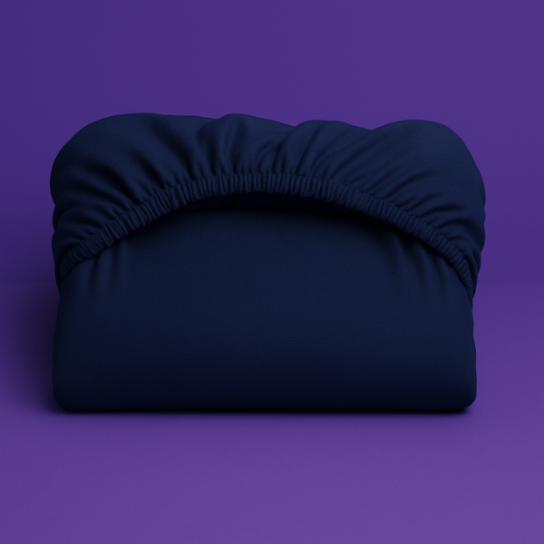 Premium navy blue fitted sheet with elastic edge displayed on a vibrant purple background. The sheet features a smooth, wrinkle-resistant fabric with deep pockets and secure elastic banding that ensures a perfect fit on mattresses.
