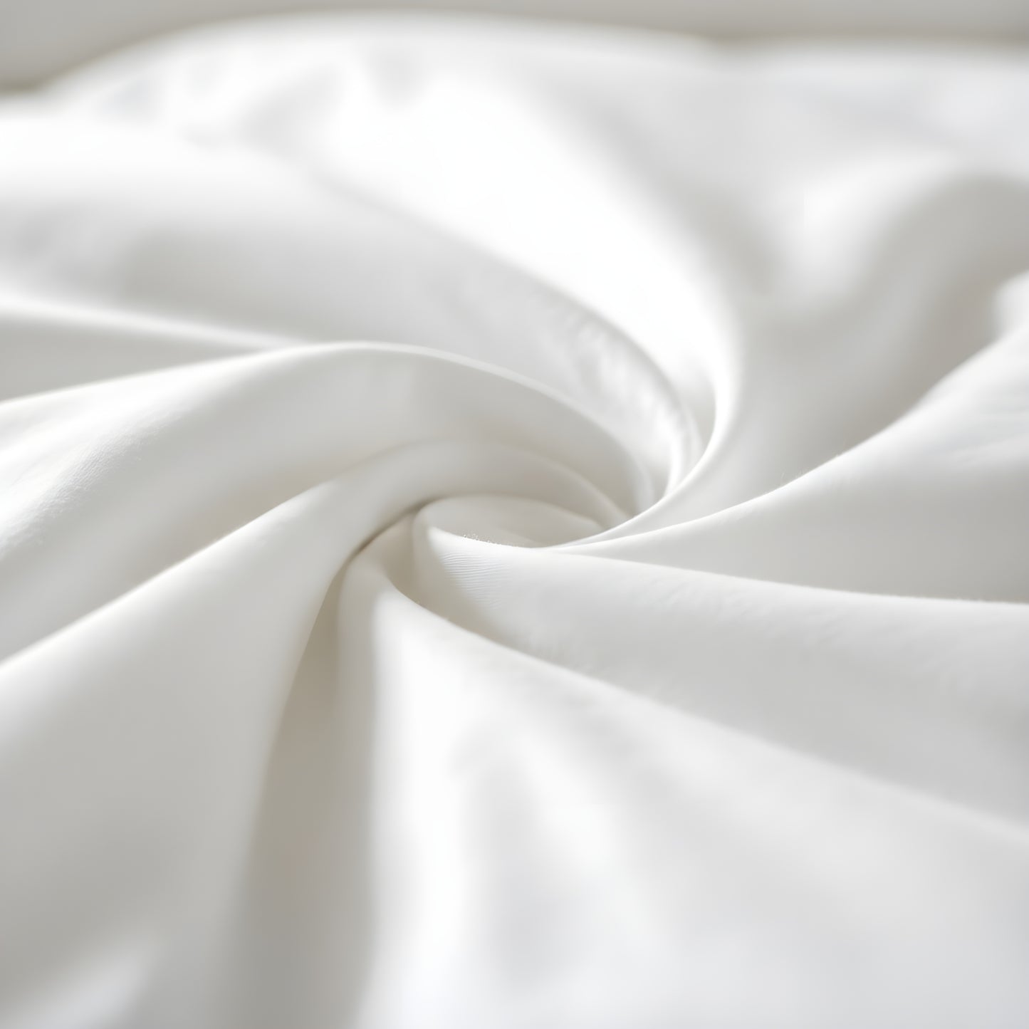 Close-up of soft white bamboo fabric with smooth folds forming a spiral pattern, highlighting its silky texture and gentle drape.