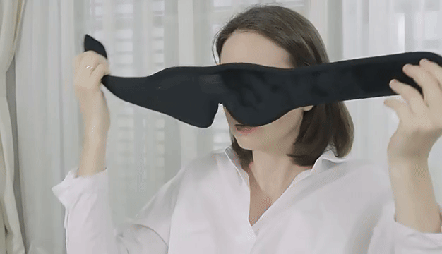 A GIF showing a person putting on the Bluetooth Sleep Mask while in her office. The person feels relaxed and starts stretching.