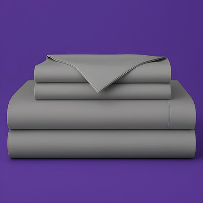 This image shows a neatly folded stack of gray bed sheets on a vibrant purple background. The stack includes what appears to be a fitted sheet, flat sheet, and pillowcases. The sheets have a smooth, crisp appearance suggesting high-quality bedding. The top sheet has a folded corner revealing the edge detail.