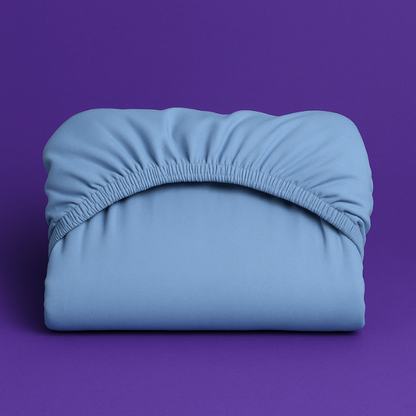 Premium light blue fitted sheet with elastic edge displayed on a vibrant purple background. The sheet features a smooth, wrinkle-resistant fabric with deep pockets and secure elastic banding that ensures a perfect fit on mattresses.