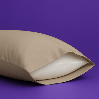 Elegant beige pillowcase with a white pillow partially visible inside, set against a rich purple background. The premium pillowcase features a clean envelope closure design that securely holds the pillow while maintaining a sleek appearance.
