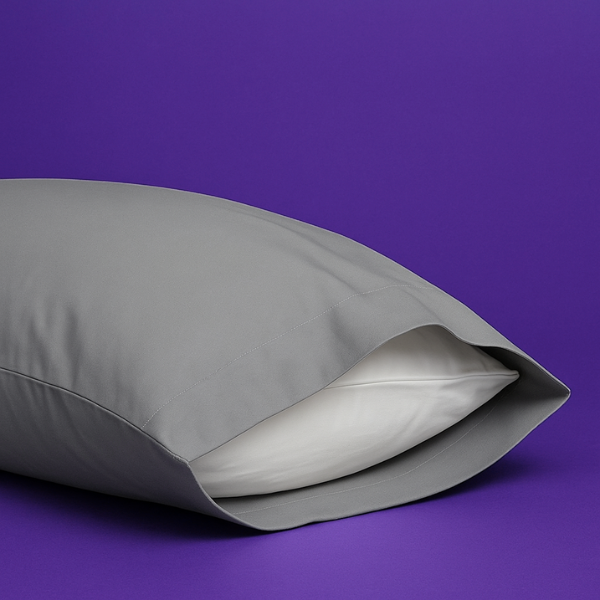 Elegant gray pillowcase with a white pillow partially visible inside, set against a rich purple background. The premium pillowcase features a clean envelope closure design that securely holds the pillow while maintaining a sleek appearance.
