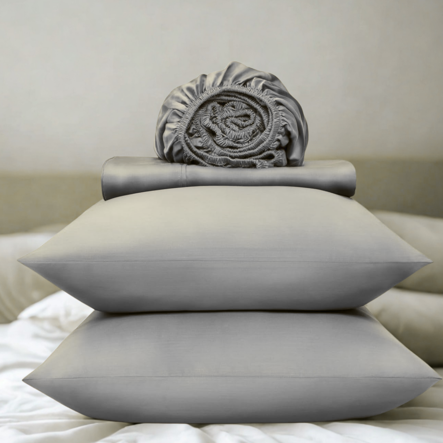Gray pillows and folded blanket on a bed with a neutral background