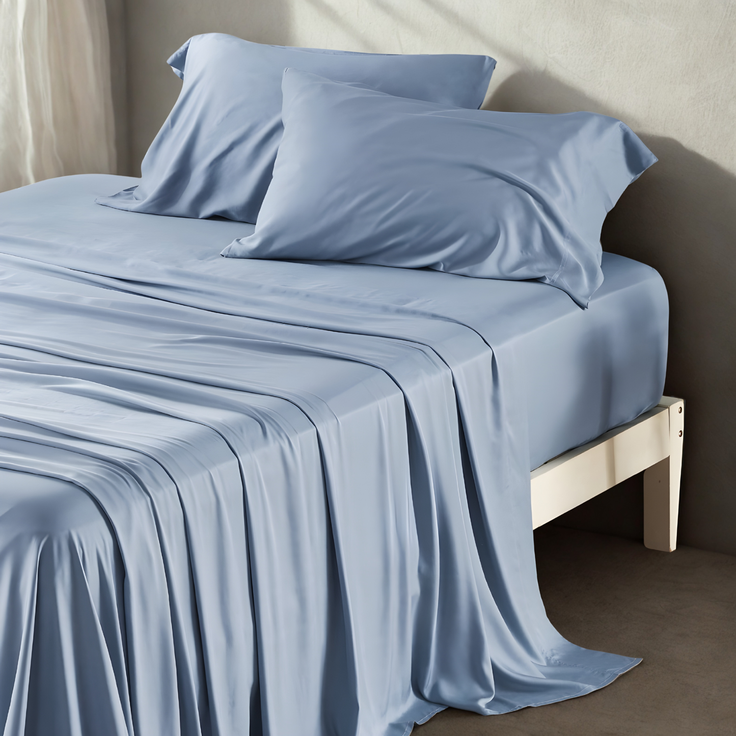 Blue bed sheets and pillows on a bed in a minimalistic room.