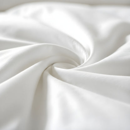 Close-up of soft white bamboo fabric with smooth folds forming a spiral pattern, highlighting its silky texture and gentle drape.