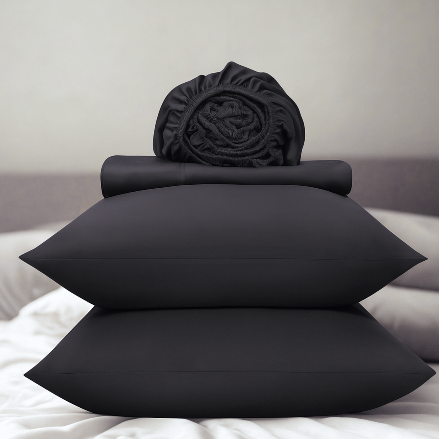 Dark grey bedding set including pillows and a fitted sheet on a bed.