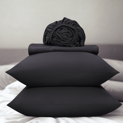 Dark grey bedding set including pillows and a fitted sheet on a bed.