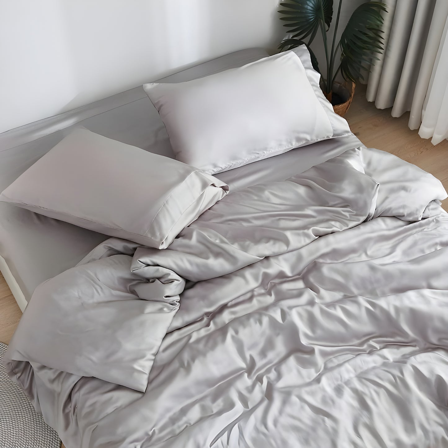 Luxurious gray bedding showcasing premium comfort with a person peacefully sleeping on soft sheets and pillows. The sleeper, wearing a light-colored top, appears comfortable and relaxed against the plush pillow and silky sheets, demonstrating the bedding's comfort benefits.