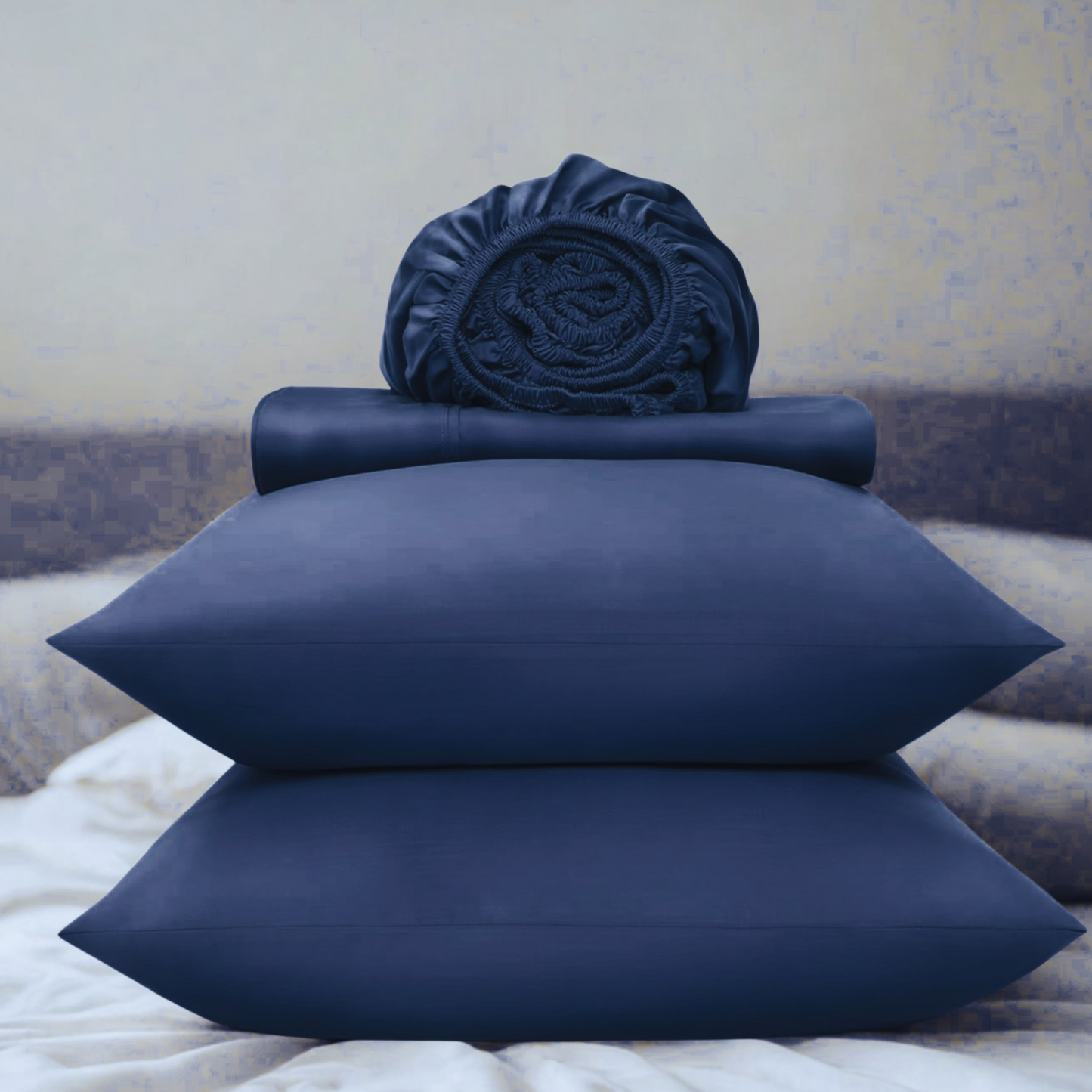 Navy blue bed sheets and pillowcases on a bed with a neutral background