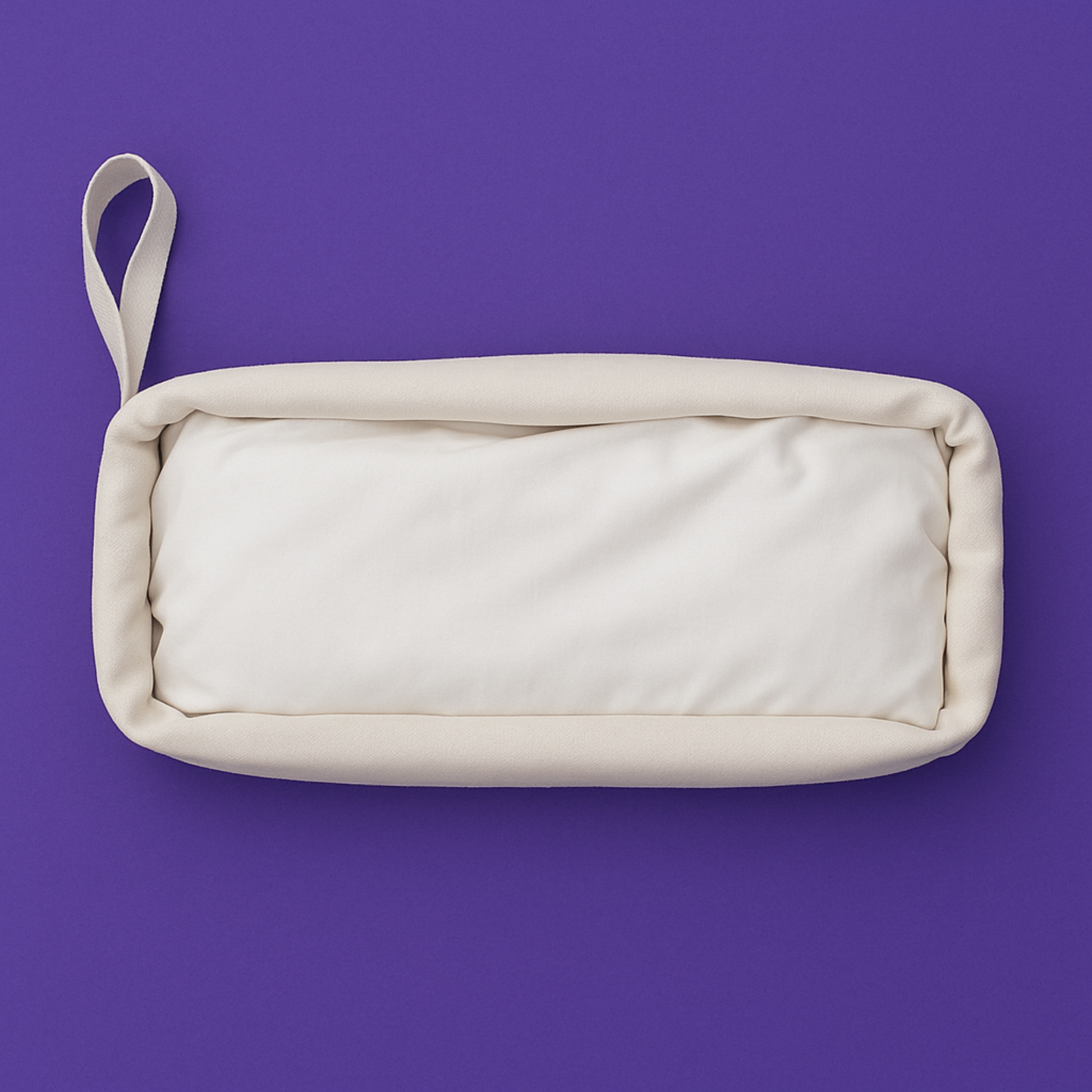 White canvas drawstring bag filled with bamboo bed sheets, displayed horizontally on a rich purple background, showcasing eco-friendly and minimalist bedding packaging.