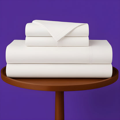 SoftlyMade premium white bamboo bed sheets neatly folded on wooden round table against purple background. Luxury bedding set with flat sheet, fitted sheet and pillowcases for comfortable sleep.